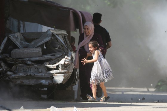 A Palestinian mother and her daughter rush for cover during an Israeli strike