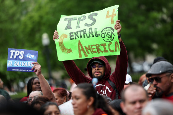 A person holds a green sign that reads "TPS 4 Central America"