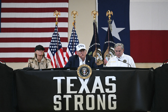 President Donald Trump and first lady Melania Trump with Texas governor Greg Abbott sitting at a table that reads, "Texas Strong"