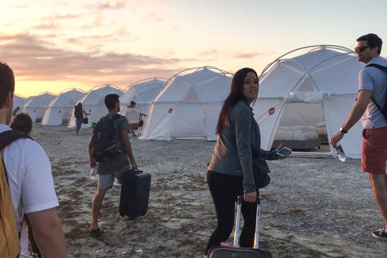 People walk towards tents at sunset