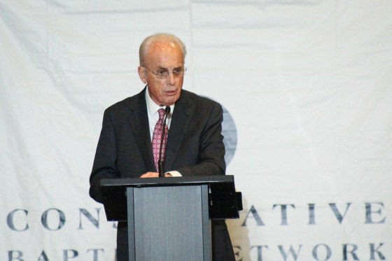 John MacArthur speaks at a podium on stage