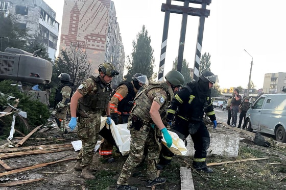 This handout picture taken and released by Ukrainian State Emergency Service on July 16, 2025 shows rescuers carrying a body from a damaged civilian installation following a Russian strike in Dobropillia, Donetsk region, amid Russian invasion in Ukraine.