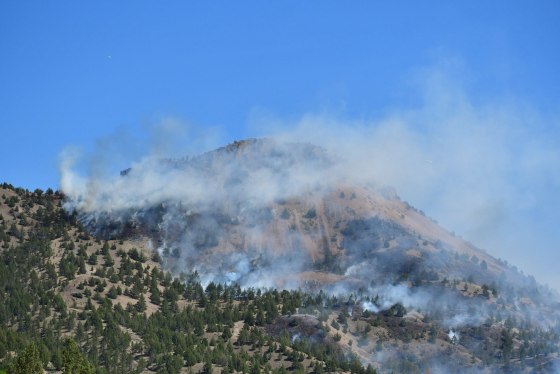 A hilltop burns with smoke surrounding it