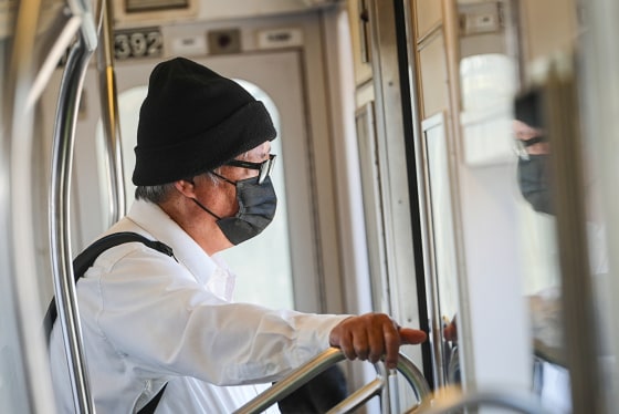 A person wears a black surgical mask on a train