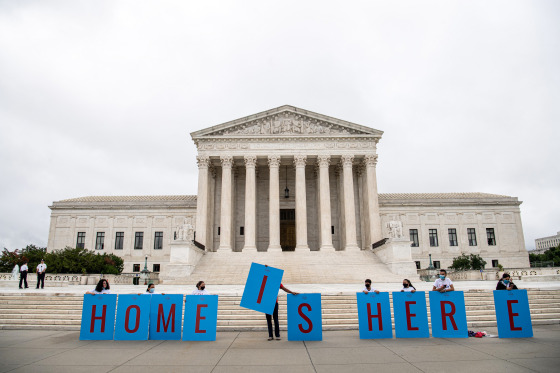 People hold signs that read "HOME IS HERE."