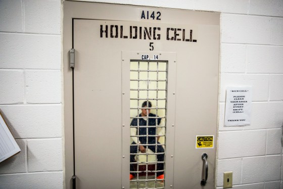 A detainee sits in a holding cell