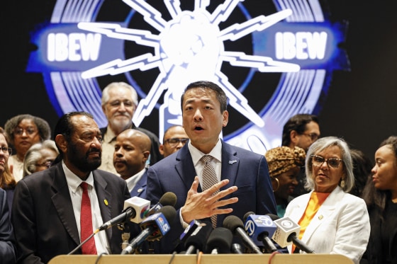 Gene Wu speaks at a podium surrounded by other people