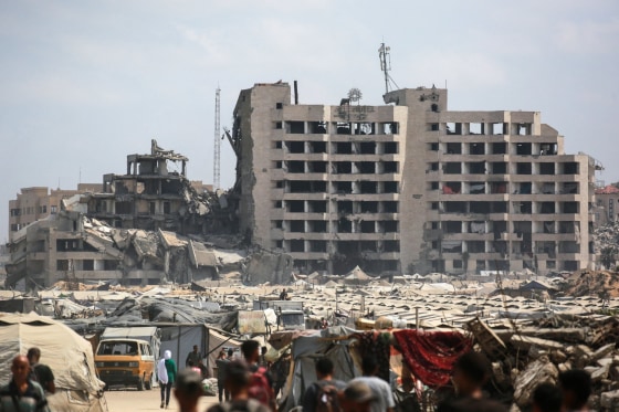 Image: Palestinians walk on a dirt road in a makeshift displacement camp on the Gaza City beachfront on Aug. 8, 2025.