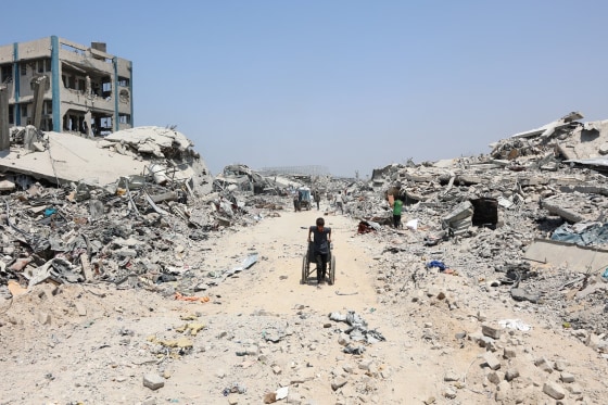Image: A Palestinian boy pulls a wheelchair past destroyed buildings in the al-Tuffah neighborhood of Gaza City on Aug. 14, 2025. 