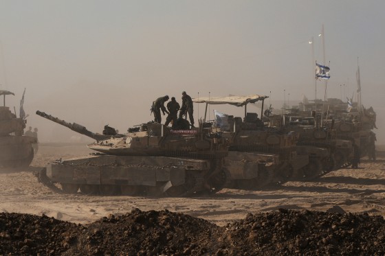 Israeli soldiers stand on top of a tank 