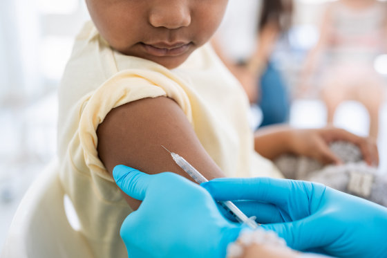 Young boy getting a shot at doctor's office and looking at needle