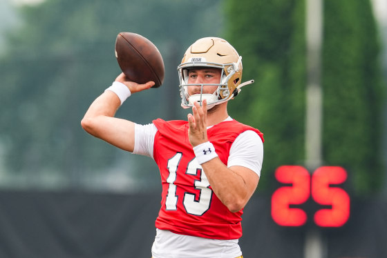 CJ Carr prepares to throw a football on the field, wearing a helmet