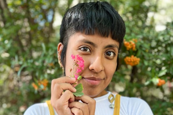 Catalina "Xochitl" Santiago holds a pink flower near her cheek