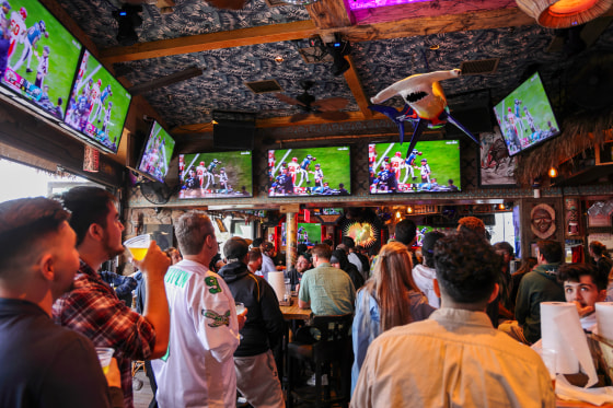 Fans watch Super Bowl at a bar.