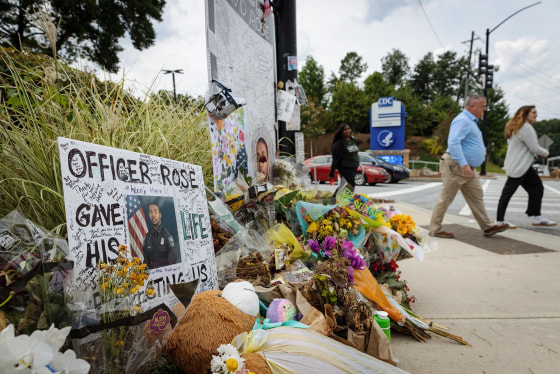 Pedestrians pass a memorial for officer David Rose at the CDC headquarters