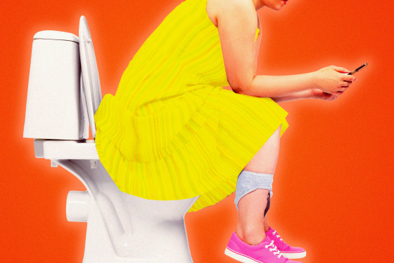 A woman sits on the toilet scrolling on her phone