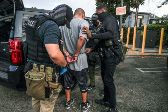 ICE agents arrest someone near a car outside