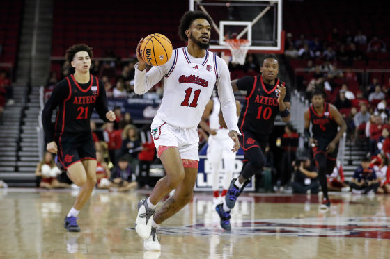 Mykell Robinson, center, holds a basketball while running on the court