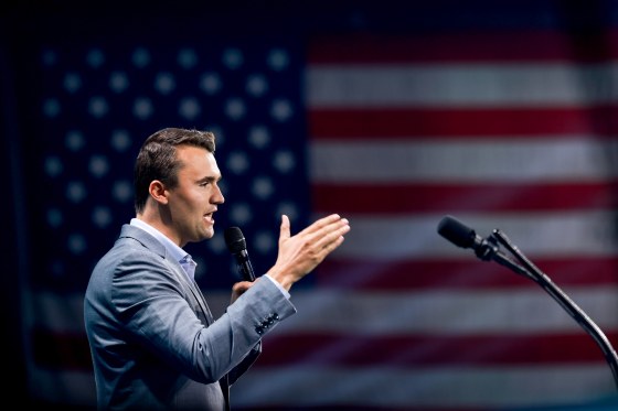 Charlie Kirk speaks on stage, American flag backdrop