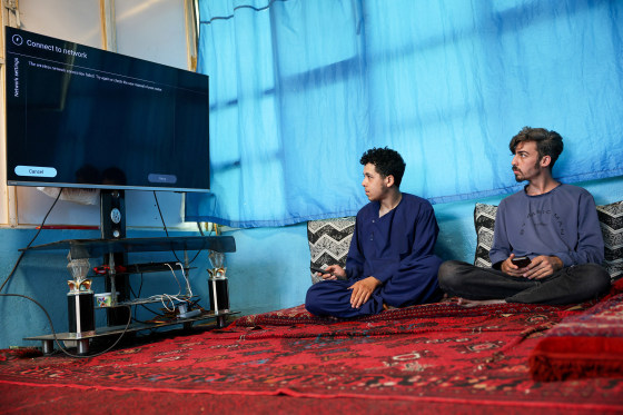 Men try to connect their smart TV to the internet inside their home, amid telecom shutdown across the country, in Kabul