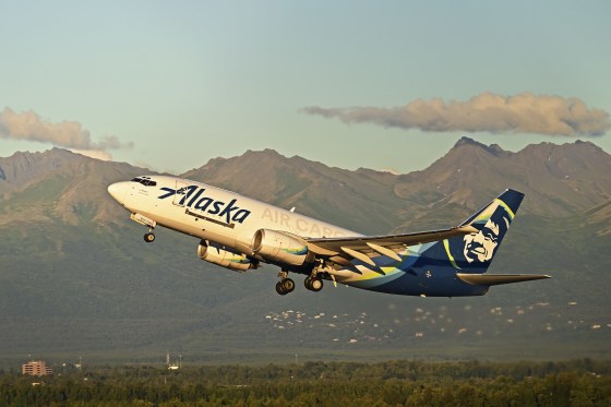 A plane takes off against the backdrop of the Chugach Mountains