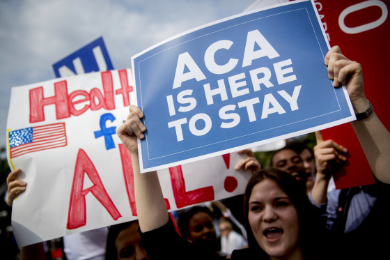 Demonstrators hold signs.