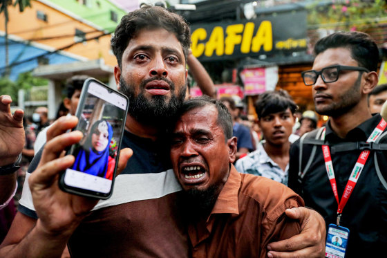 Two men crying as one shows a picture of a fire accident victim on his mobile phone