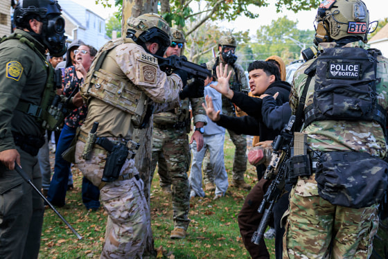 An officer with Customs and Border Protection points a crowd control weapon at a protester in Chicago's East Side neighborhood on Oct. 14, 2025.
