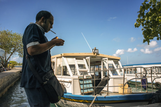 A man lights a cigarette in the Maldives islands harbor