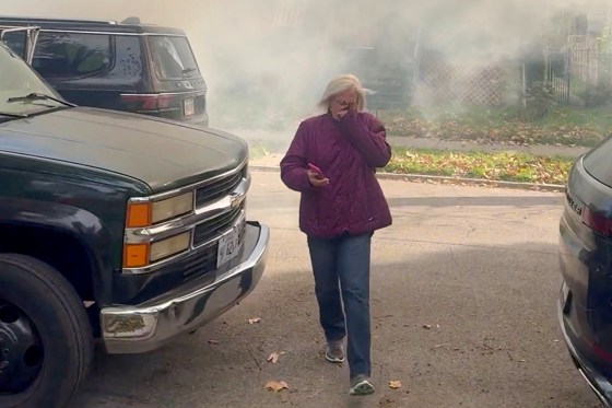 A woman cover her mouth as she escapes from what appears to be smoke or tear gas.