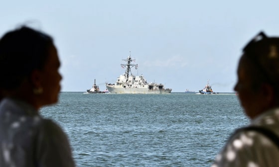 People watch the USS Gravely, a US Navy warship, departing the Port of Port of Spain.
