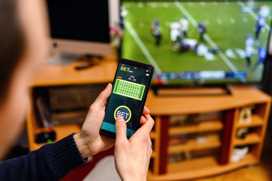 Young men using smart phone for sports betting.