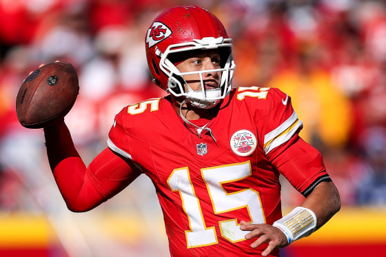 Patrick Mahomes holds a football on the field preparing to throw it