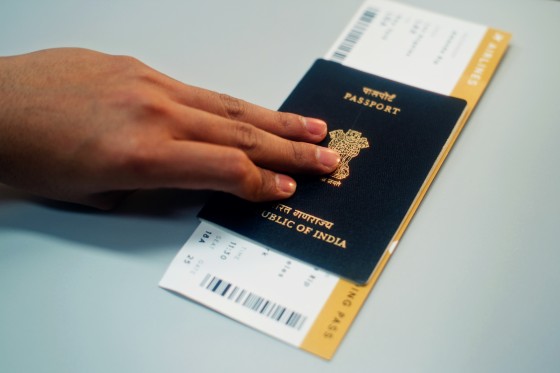 Close Up of Passenger Putting Indian Passport with Airplane Ticket on Airport Check-in Counter