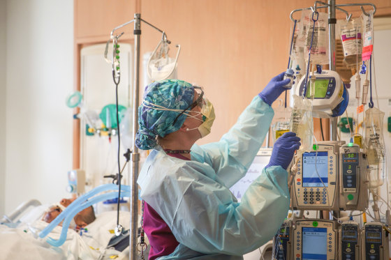 A nurse grabs a vial inside of a room with a patient inside