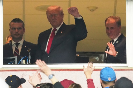 President Donald Trump, center, gestures to the crowd alongside Defense Secretary Pete Hegseth, left, and Washington Commanders owner Josh Harris, as they attend an NFL football game between the Commanders and the Detroit Lions on Sunday.