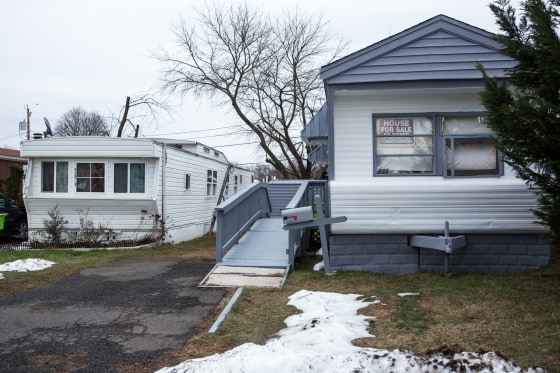 A '"for sale" sign is seen in a window of a mobile home