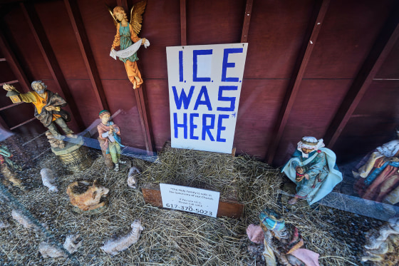 An "ICE WAS HERE" sign over an empty manger at a Nativity scene