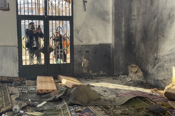 A man takes a photo of the aftermath of the explosion inside Imam Ali ibn Abi Talib Mosque in the Wadi al-Dahab neighborhood of Homs on Friday.