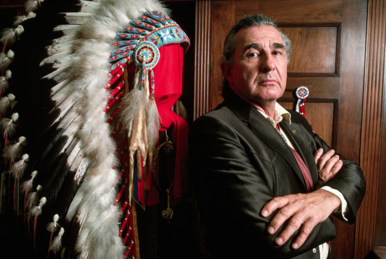 Ben Nighthorse Campbell poses next to a Native American headdress