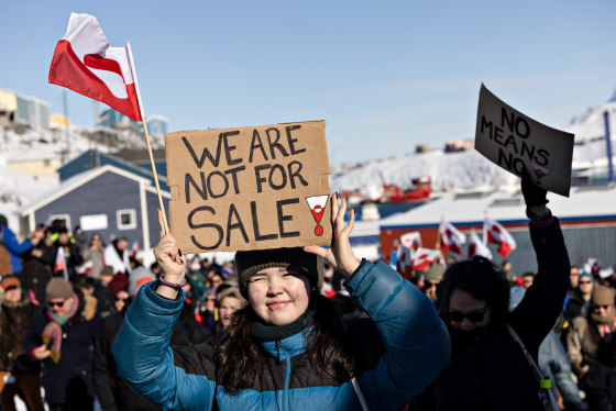 A protester holds a sign outside reading 'We are not for sale'
