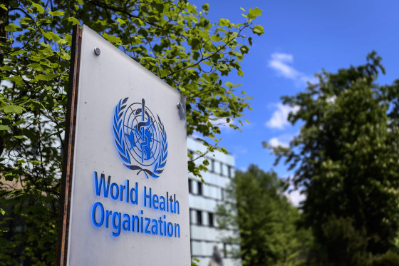 The blue World Health Organization logo is displayed on a sign outdoors. 