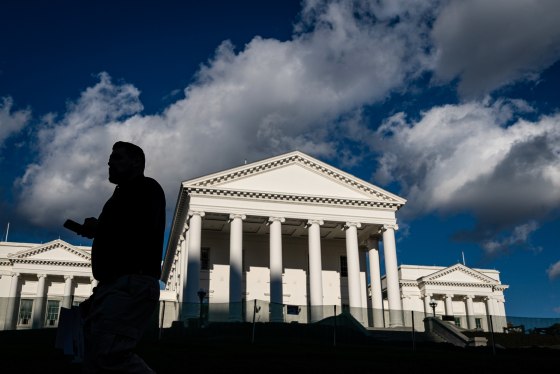 The exterior of the Virginia State Capitol, the silhouette of a person walks by it