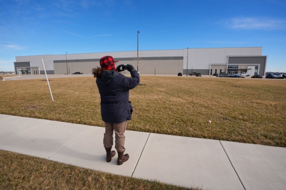 A man takes photos of a warehouse as federal officials tour the facility to consider repurposing it as an ICE detention facility Thursday, Jan. 15, 2026, in Belton, Mo. 