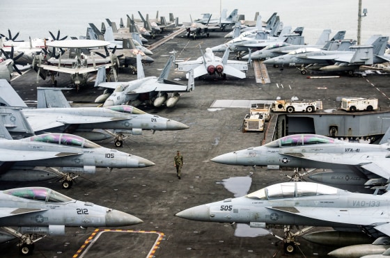 A US Navy officer walks past fighter jets parked on the flight deck of the Nimitz-class aircraft carrier USS Abraham Lincoln
