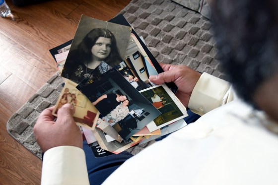Derrick Johnson, whose mother's body was one of 189 left to decay in the Return to Nature Funeral Home in Penrose, Colo., holds photos of her in Colorado Springs, on Thursday.