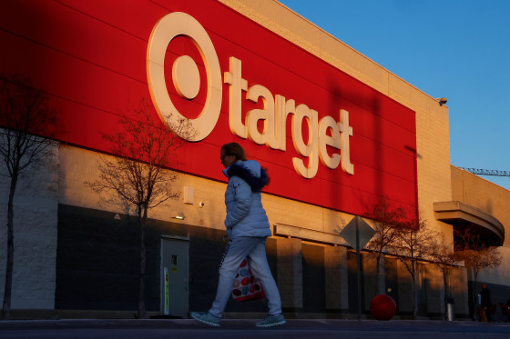 A Target retail store sign is seen while a woman walks past it.