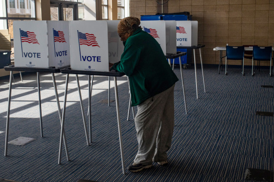 A voter cast their vote while standing in the middle of a room.