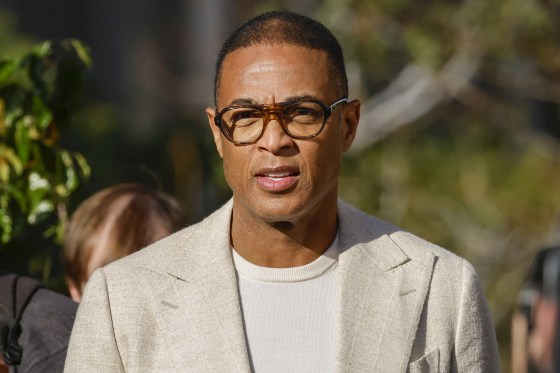 Television Journalist Don Lemon walking outside court while wearing a beige suit and thin sweater. 