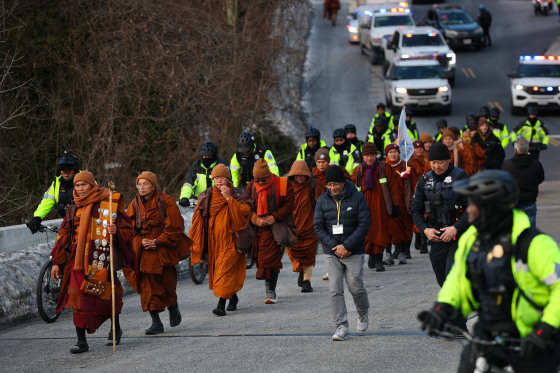 A group of Buddhist Monks walk across a bridge to reach Washington DC
